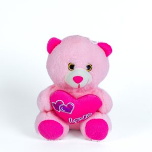 בובה של דוב ורוד יושבת ומחזיקה לב ורוד עם הכיתוב "Love".