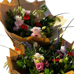 שני זרי פרחים עטופים בנייר חום, עם פרחים בצבעים ורוד, אדום, לבן וסגול, ועלי ירק.