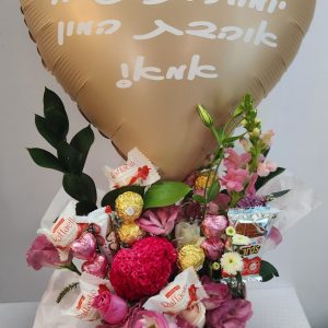 זר פרחים ומתוקים בתוך קופסה ורודה, מעליו בלון בצורת לב עם כיתוב בעברית.