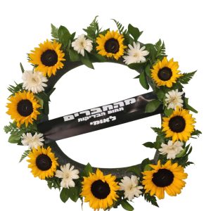 זר פרחים עגול, עשוי חמניות צהובות וחרציות לבנות, עם סרט שחור ועליו כיתוב לבן: "מהחברים, תחום הבדיקות הלא