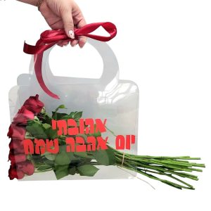 יד אוחזת בשקית שקופה עם ורדים אדומים וסרט אדום, ועליה כתוב בעברית "אהובתי יום אהבה שמח".