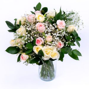 זר פרחים גדול בוורוד ולבן, עם פרחי גבס ועלי ירק, מונח באגרטל זכוכית על רקע לבן.