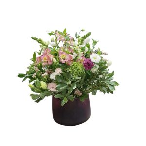 זֵר פרחים גדול וצבעוני, הכולל פרחים לבנים, ורודים וסגולים, עומד בתוך עציץ סגלגל כהה.