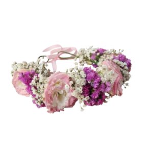 זר פרחים לראש, עשוי מפרחים ורודים, סגולים ולבנים קטנים, עם סרט ורוד לקשירה.