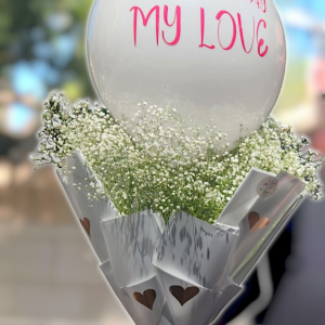 זר פרחים עם בלון לבן ועליו הכיתוב "יום הולדת שמח אהוב/ה שלי" בורוד, עטוף בנייר לבן עם לבבות חומים וקשור בסרט ורו