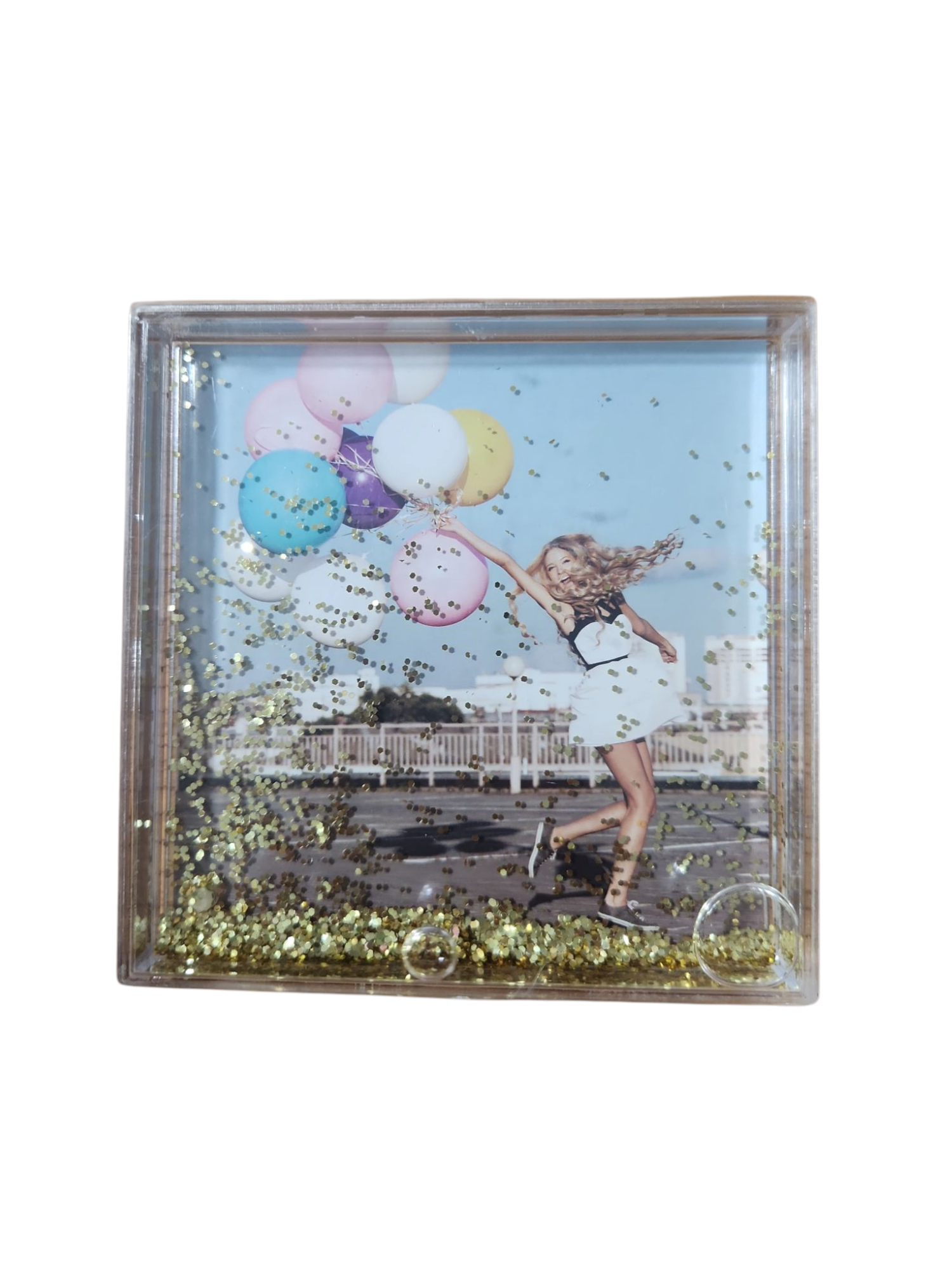 מסגרת תמונה שקופה עם נצנצים זהובים, בתוכה תמונה של אישה מחייכת רצה עם בלונים צבעוניים.
