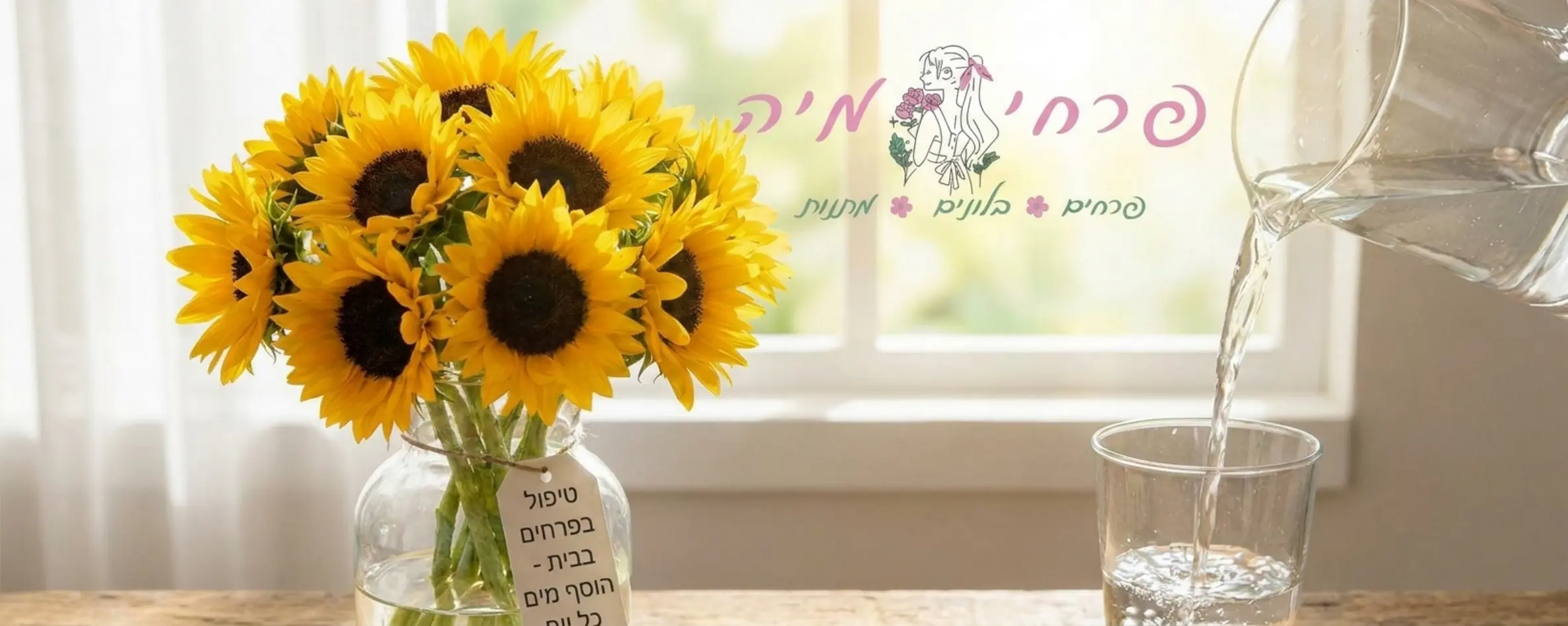 תמונה מוארת ויפה של אגרטל זכוכית שקוף מלא במים צלולים ובו זר חמניות טרי, לידו מזמרה מקצועית וכוס מים הממחישה את פעולת השקיית הפרחים בבית