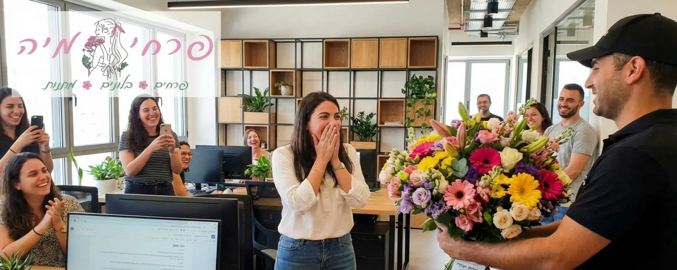 אישה יושבת במשרד מודרני מול מחשב ומופתעת בשמחה רבה כששליח מגיש לה זר פרחים צבעוני ועשיר, סביבה קולגות מחייכים