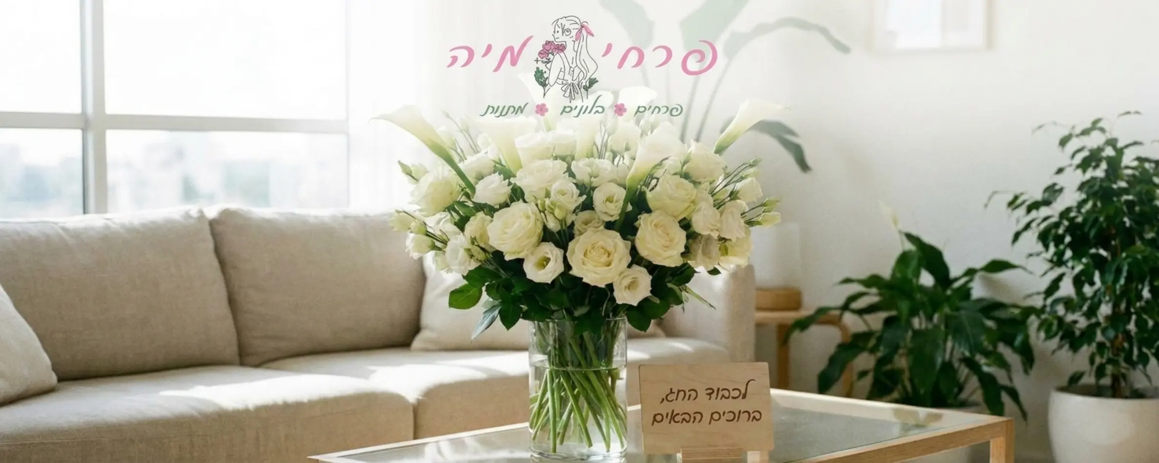 זר פרחים לבן ועשיר הכולל ורדים ושושן צחור מונח בתוך אגרטל זכוכית שקוף על שולחן סלון מודרני מואר באור טבעי