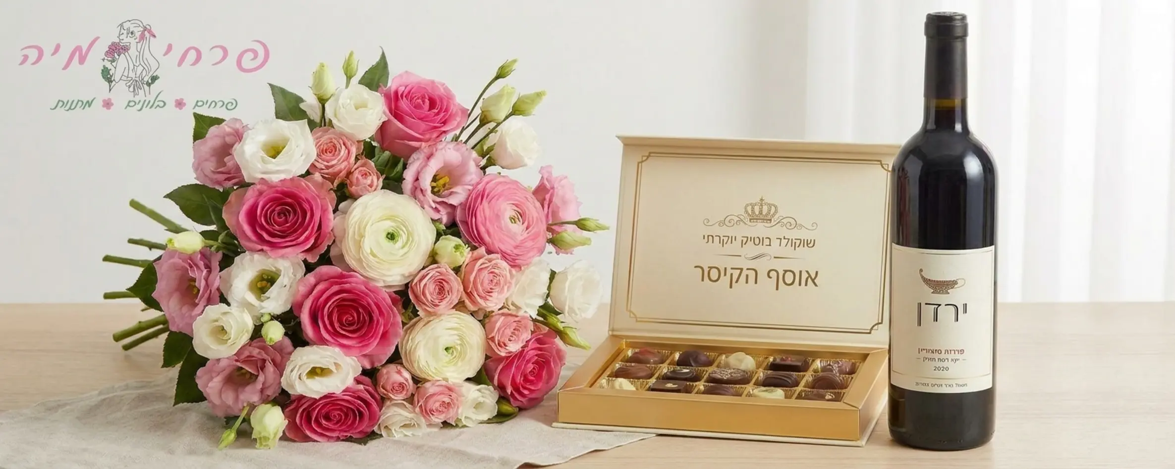 תמונה המדגימה שילוב של זר פרחים צבעוני בגווני ורוד ולבן לצד מארז שוקולד יוקרתי ובקבוק יין, מסודרים באלגנטיות על רקע בהיר ונקי