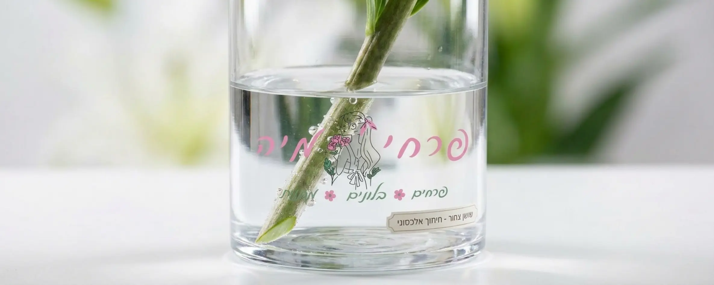 תצלום תקריב של אגרטל זכוכית שקוף עם מים נקיים, המציג חיתוך אלכסוני של גבעול שושן צחור מתחת לפני המים, באווירה נקייה ומקצועית