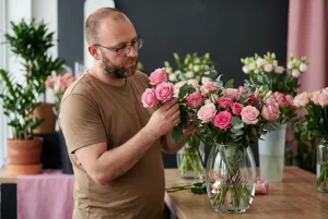 צוות החנות בוחן בקפידה ורדים טריים ומסדר אותם באגרטל זכוכית מעוצב.