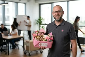 מנהל לקוחות אוחז בידו מארז מתוק ומושקע, מוכן לשילוח, כשברקע משרד דינאמי - מסמל שליטה במצב ותיקון טעויות בסטייל.